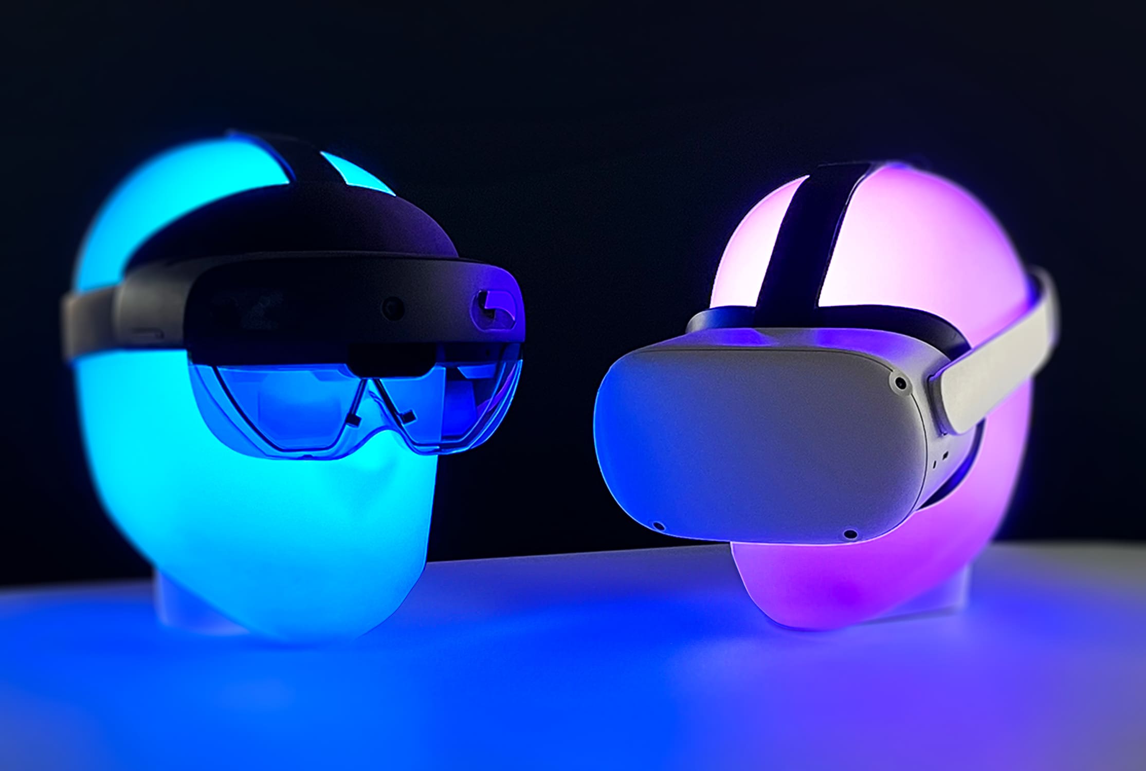 Zwei Headsets auf leuchtenden Ständern, eines für Augmented Reality (AR) und das andere für Virtual Reality (VR), beleuchtet in blauem und pinkem Neonlicht, repräsentieren die moderne AR- und VR-Technologie.